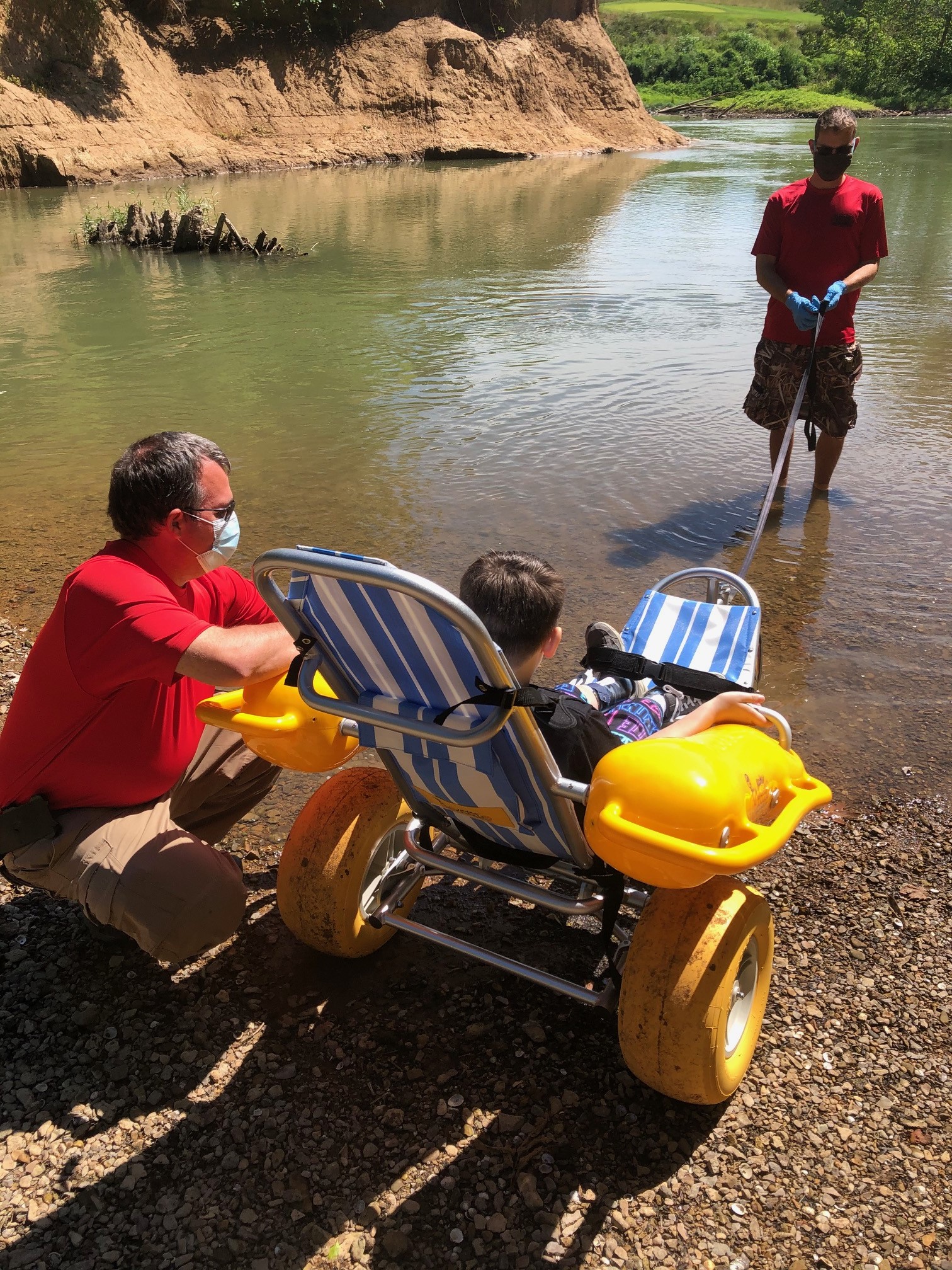 Boy in water wheelchair entering lake for recreation
